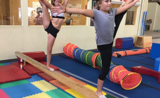 gymnasts performing a balance on a balance beam